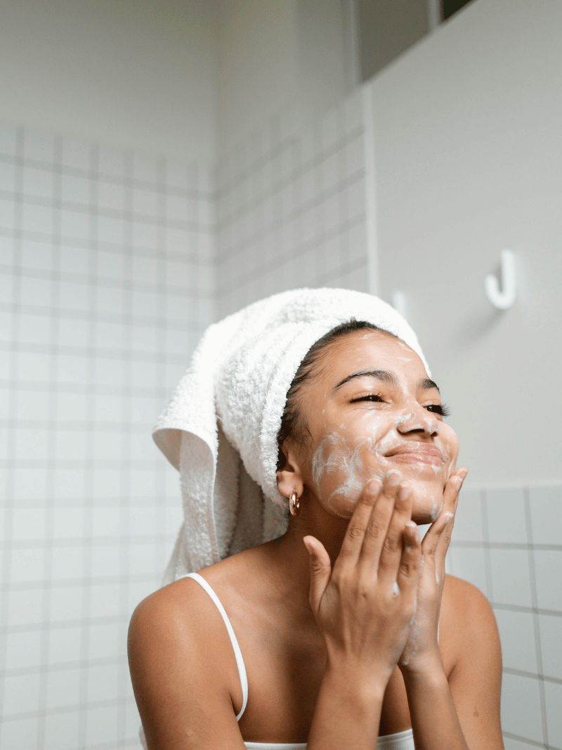 woman cleansing face in white bathroom