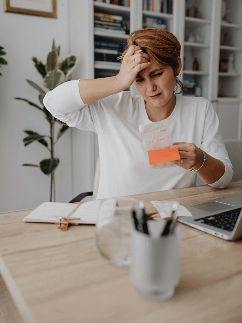 older woman in white shirt looking at receipts in frustration