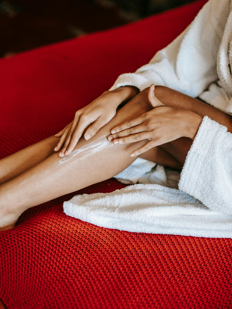 woman on red couch rubbing lotion on dry skin
