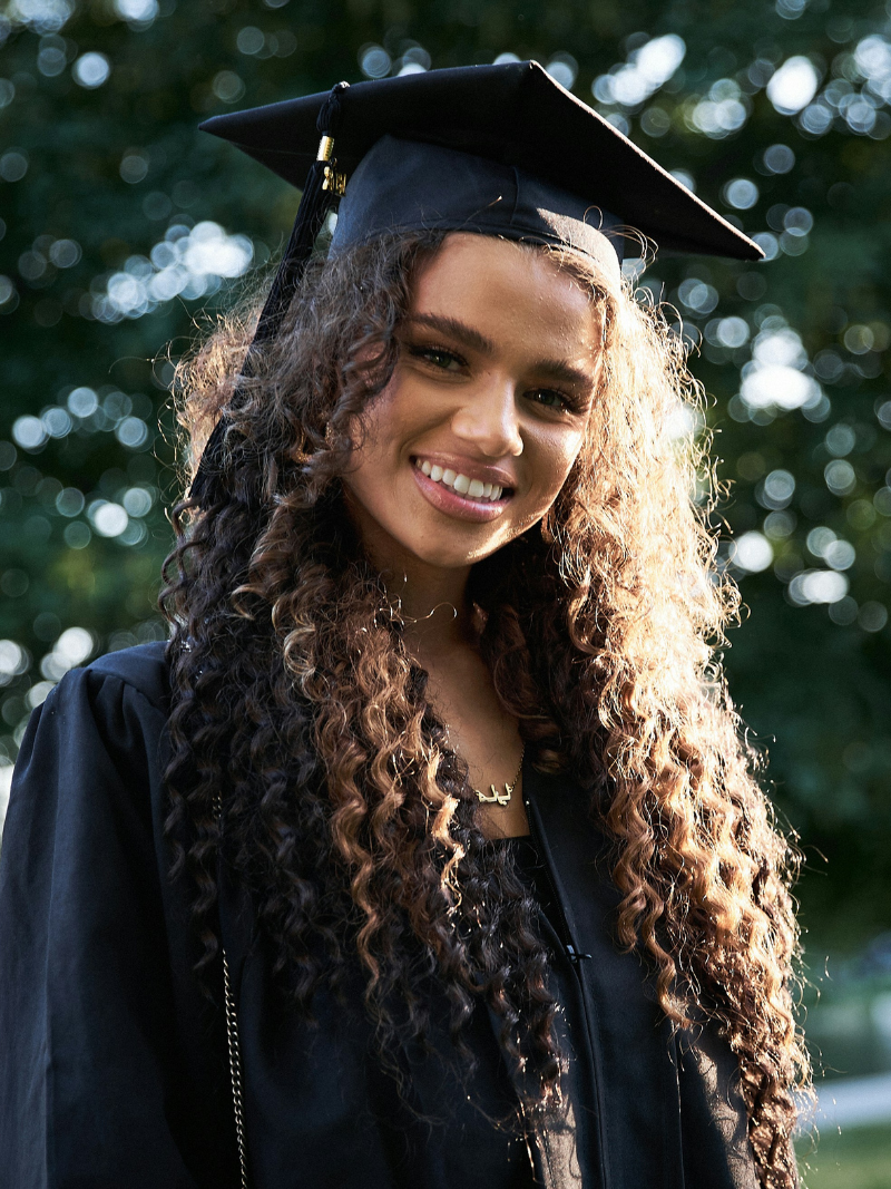 woman with curly hair in a cap and gown