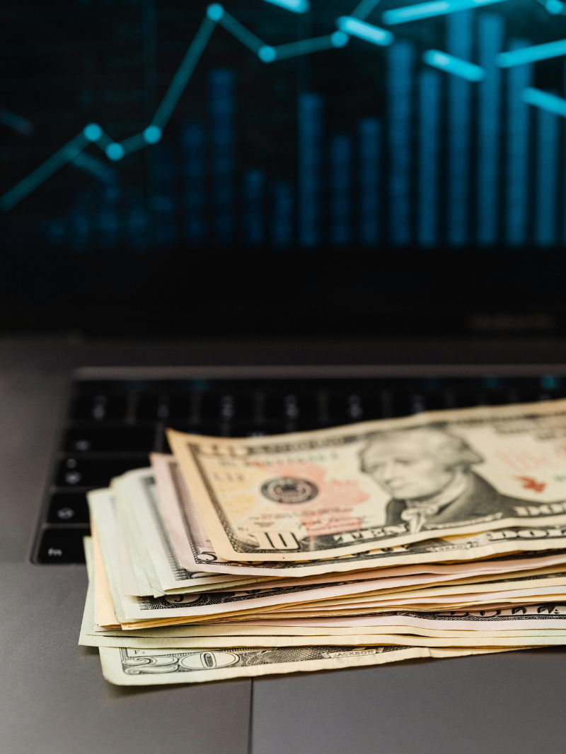 cash on a laptop in front of stock market visual