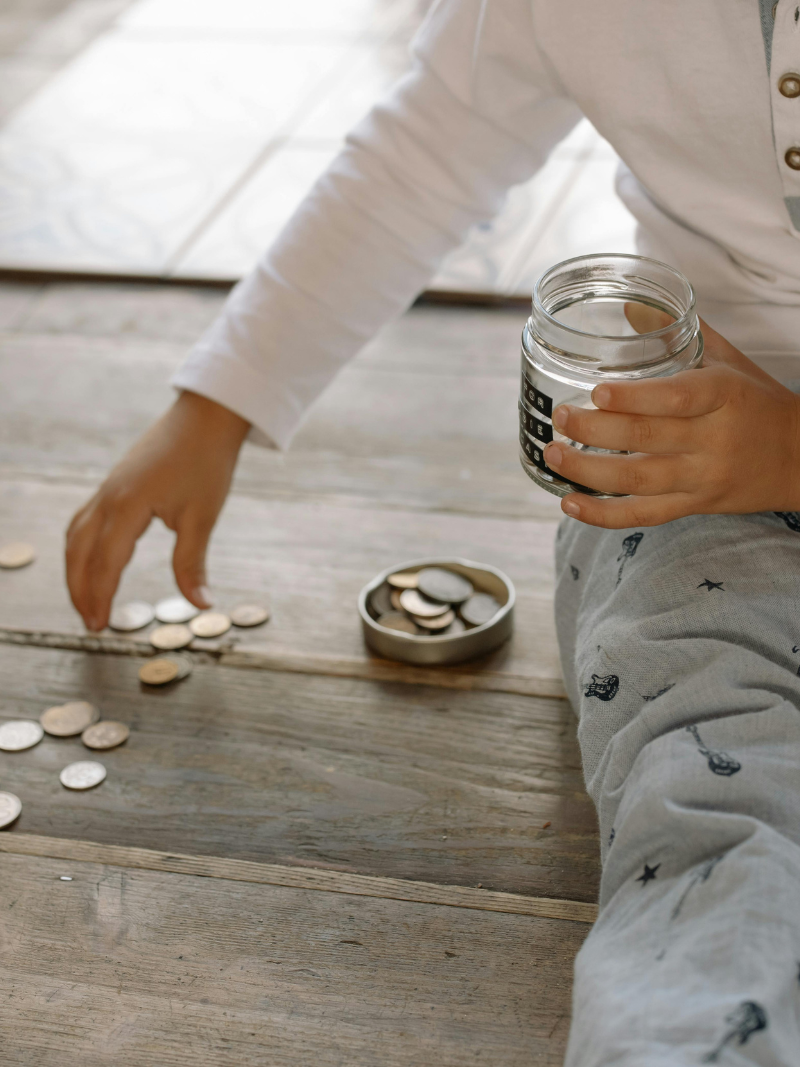 child picking up coins to put into a savings jar